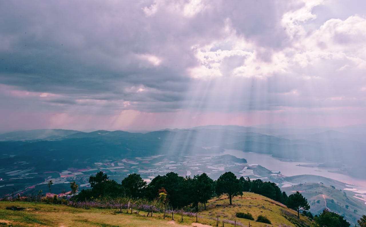 Sunlight beams through clouds over a mountain, offering a breathtaking view of nature.